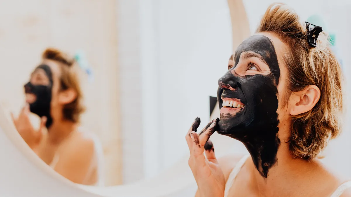 woman applying black clay face mask
